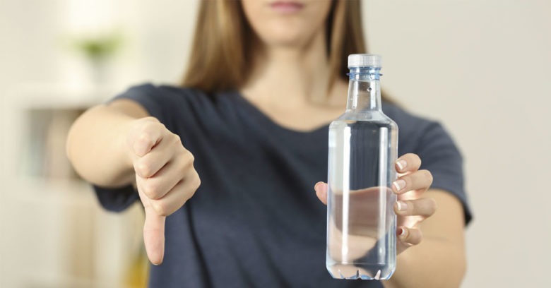 mulher segurando garrafa de água de qualidade ruim e fazendo sinal de negativo