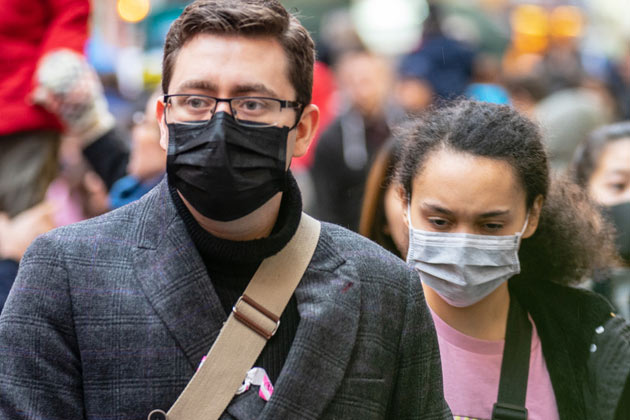 Homem e mulher utilizando máscaras na rua fazendo valer o cumprimento das informações do coronavírus.